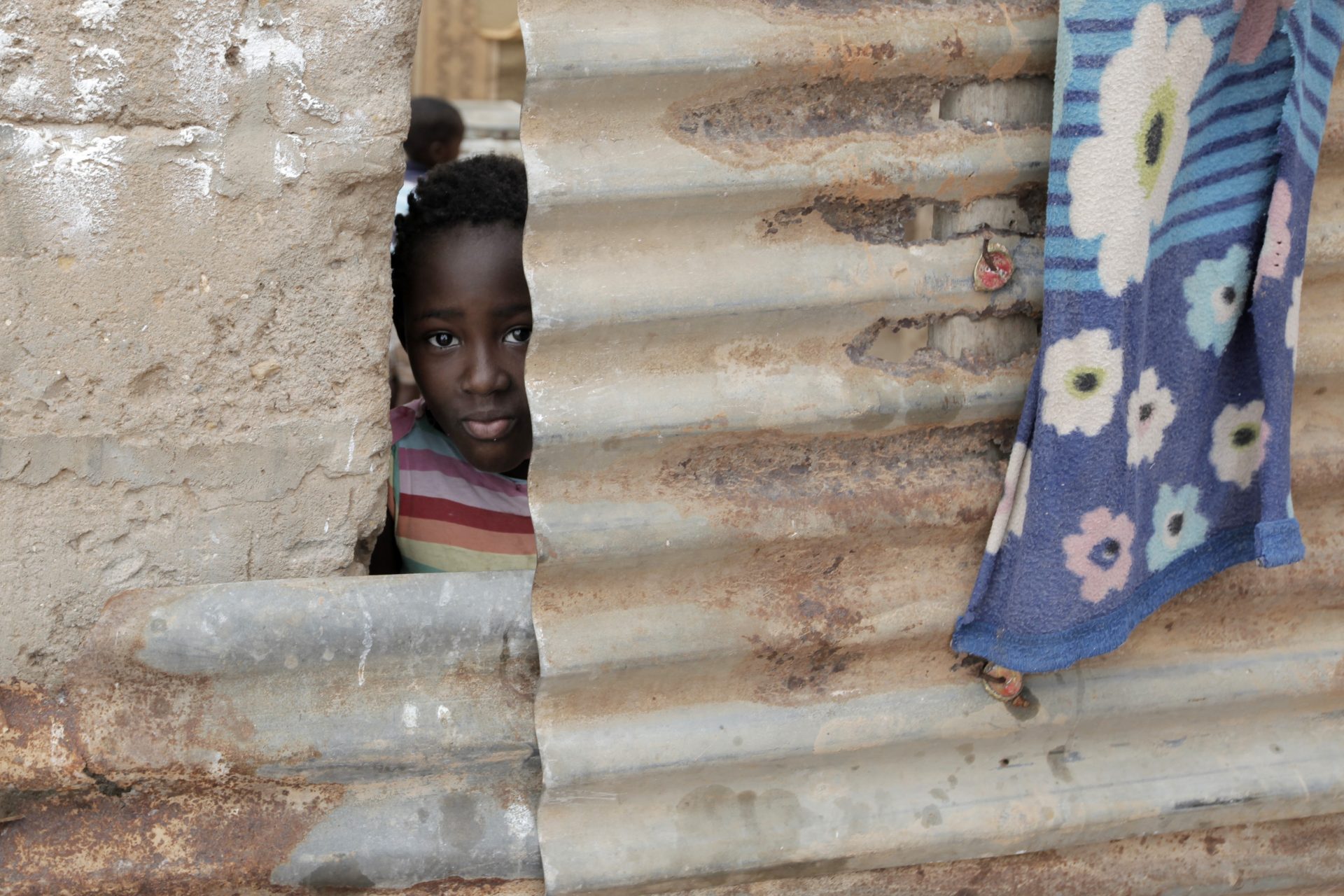 Uma criança espreita através das chapas de zinco usadas na construção de sua casa, no musseque de Zamba 2 que se estende até à cidade de Luanda, 2 novembro de 2015. Luanda é a capital de Angola, tem cerca de 6 milhões de habitantes a maior parte da população vive em bairros periféricos à cidade que é uma das cidades mais caras do mundo. PAULO CUNHA/LUSA